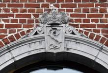 Avenue de la Brabançonne 82, Schaerbeek, entrée du commerce, clef sculptée d’un L(éopold)(?) et d’une couronne royale (© APEB, photo 2016).